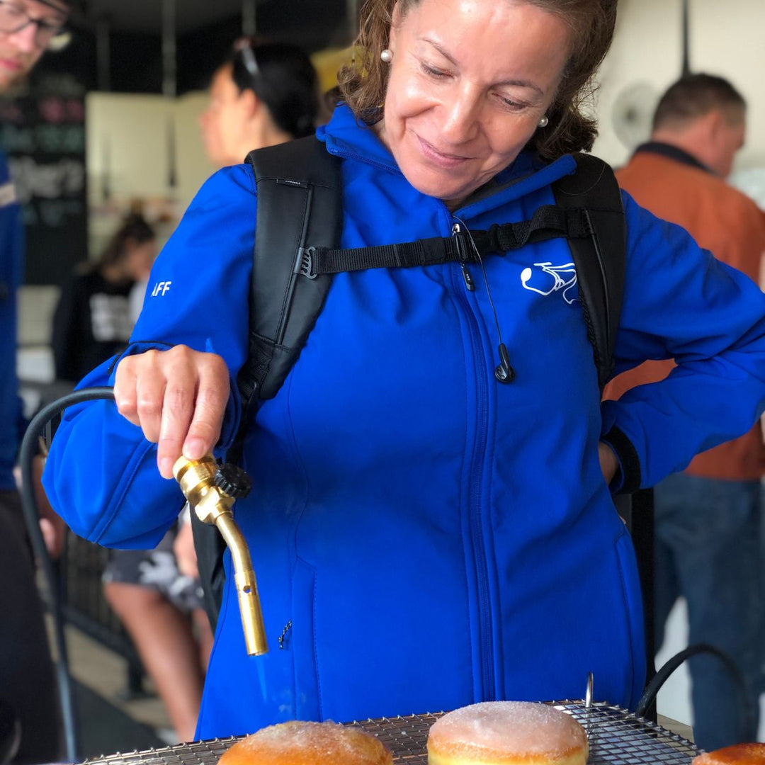 Best-restaurants-Edmonton-Donut-Bike-tour-international-donut-day-in-Edmonton-Edmonton-things-to-do-friday-date-ideas-food-bike-tour-women-in-blue-jacket-decorating donut-and-smiling-alberta-tours